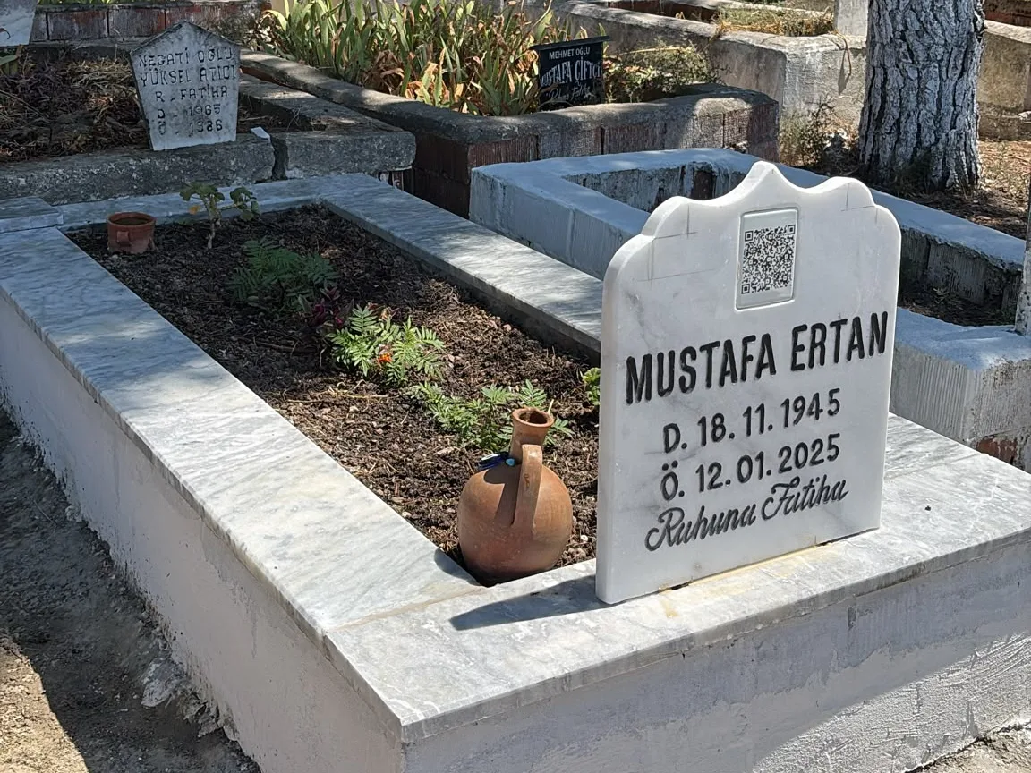 Mustafa Ertan'ın mezar taşı. Taşın üst ortasında, adın hemen üstünde kazınmış bir QR kod duruyor.